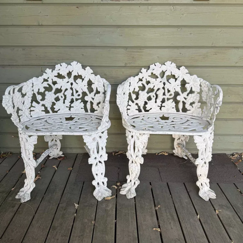 A pair of cast aluminium garden seats The seats with fruiting vine ornament to the back