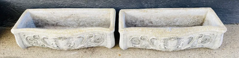 A pair of rectangular planters with a serpentine shaped front with neo classical cherub decoration. 74.5cms wide x 32cms deep x 21cms high