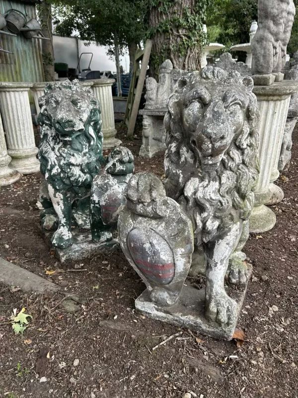 A pair of cast reconstituted stone garden ornaments The ornaments in the form of lions, each supporting a shield