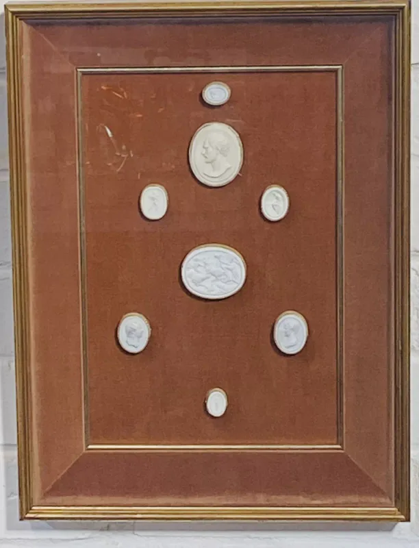 A framed and glazed wall hanging case displaying eight plaster 'Grand Tour' intaglios, case