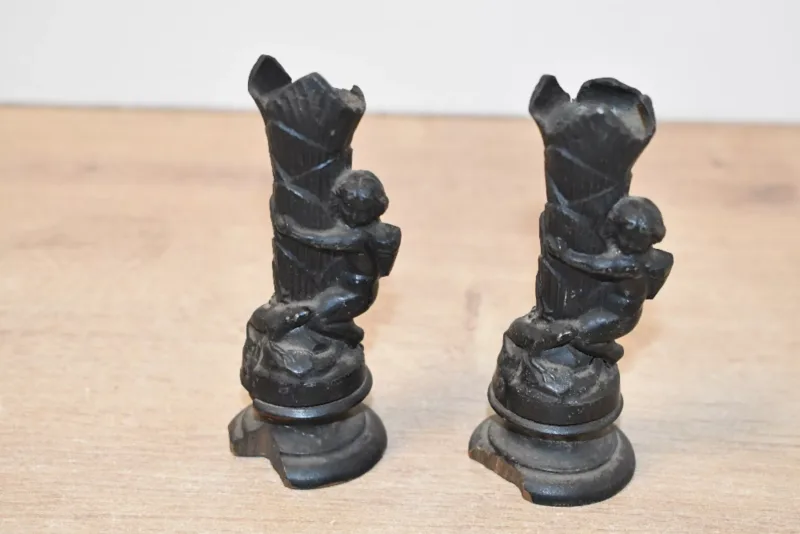 Two small 19th-century cast metal figural candlesticks, each featuring a putto-type figure upon a tiered palm leaf-like stem