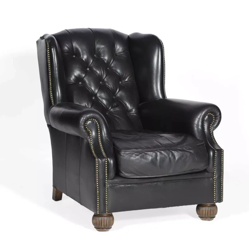 A Tetrad Black Leather Wing Armchair the deep buttoned back between shaped wings, the scrolled arms close nailed throughout, with a loose seat cushion
