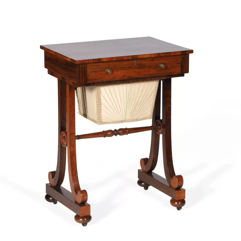 A William IV Rosewood Work Table circa 1835, the rectangular crossbanded top above a frieze drawer with turned handles and a pleated work bag below