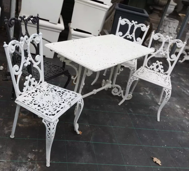 A Victorian style rectangular garden table and four chairs The rectangular topped table with pierced decoration, lion mask supports and scrolling feet