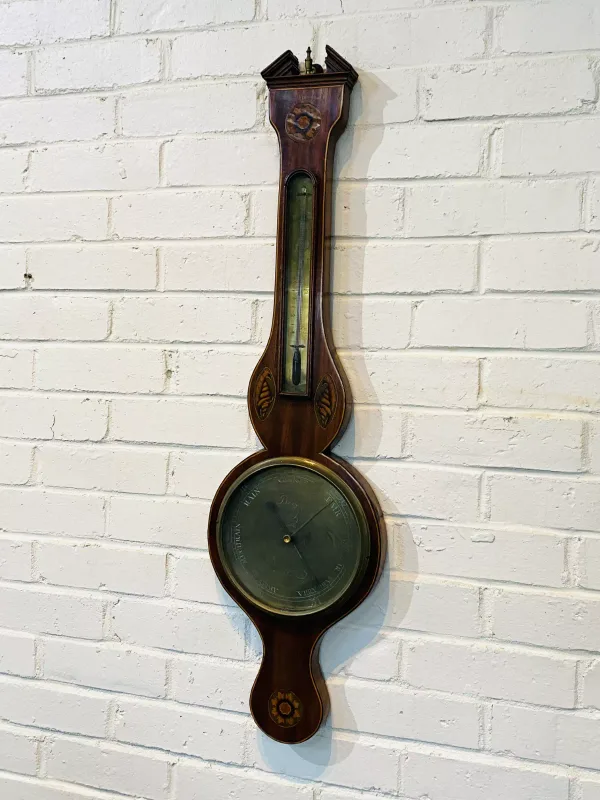 A Georgian mahogany wheel barometer with shell and marquetry inlaid decoration, the dial