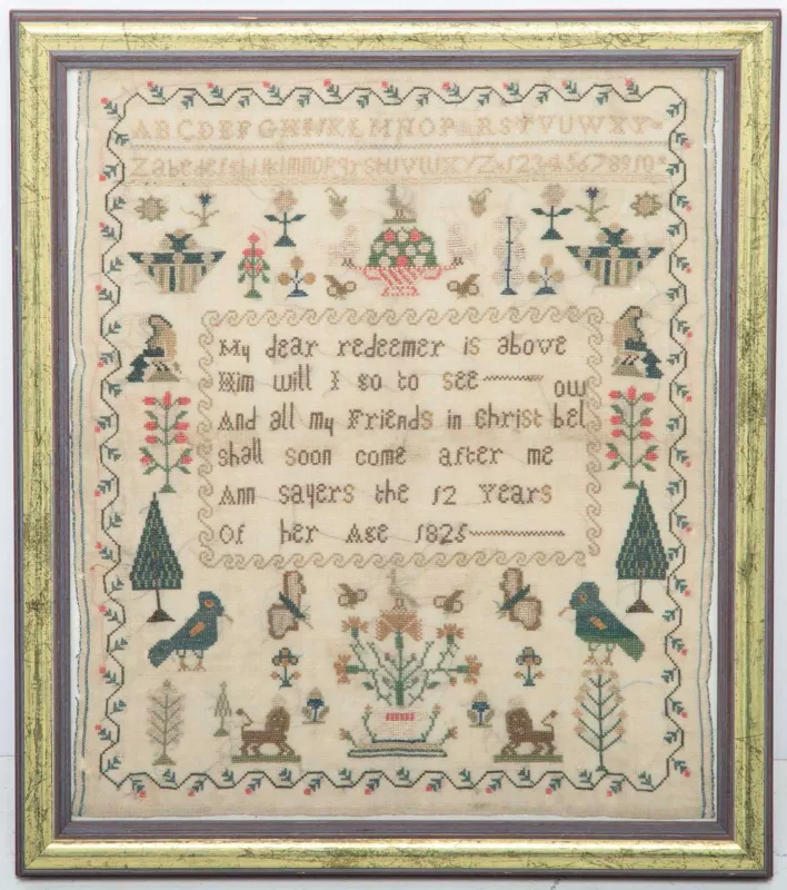 A George IV Needlework Sampler by Ann Sayers, 1825, worked in coloured silks with bands of alphabets and numerals above baskets of flowers and seated figures