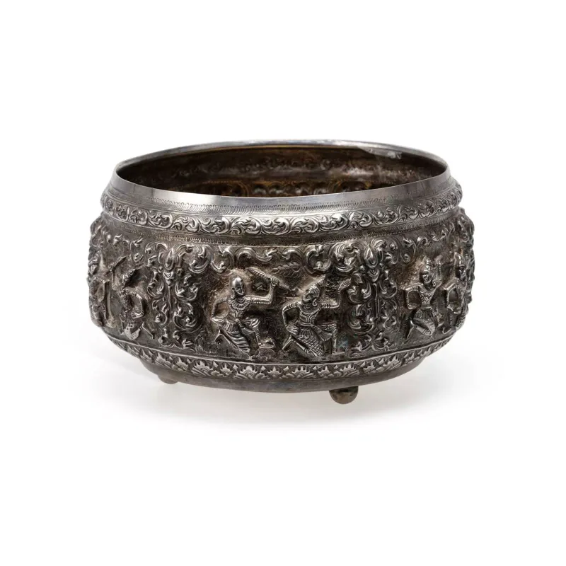 A Burmese Silver Offering Bowl 20th Century, decorated embossed in high relief with figural panels within foliate and scroll borders