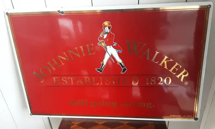 advertising sign for the Scottish whisky brand Johnnie Walker, featuring the iconic "Striding Man" - emaillerie belge - Enamel sign - Enamel