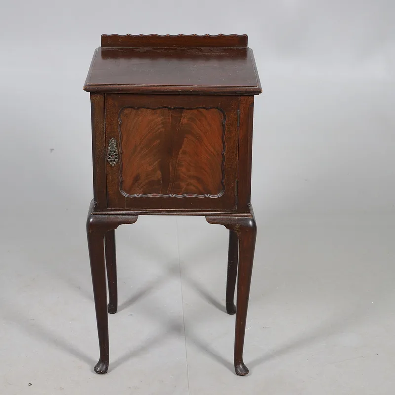 A mahogany pot cupboard, with a panelled door with a decorative escutcheon, raised on cabriole style supports.
