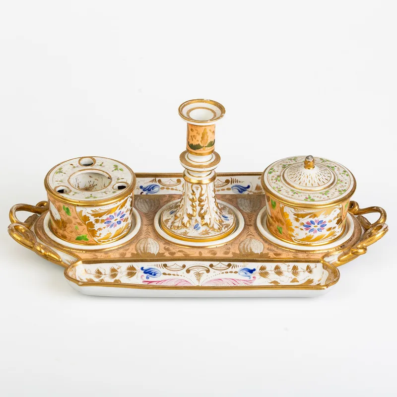 An early 19th century Bloor Derby porcelain standish, the tray base with pen gutters, having inkwell, lidded pot and central candle stick