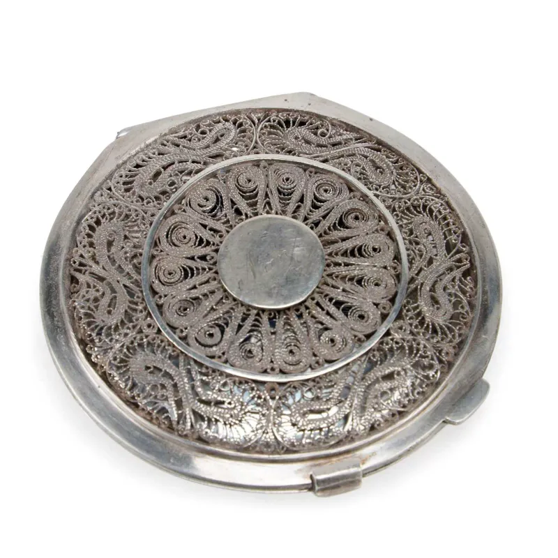 An Iraqi Silver And Niello Compact 20th Century, of circular form, with a filigree hinged cover around a central cartouche