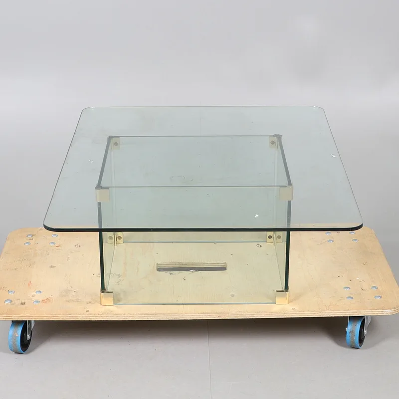 A modern rectangular glass coffee table, raised on a rectangular base with metallic features,