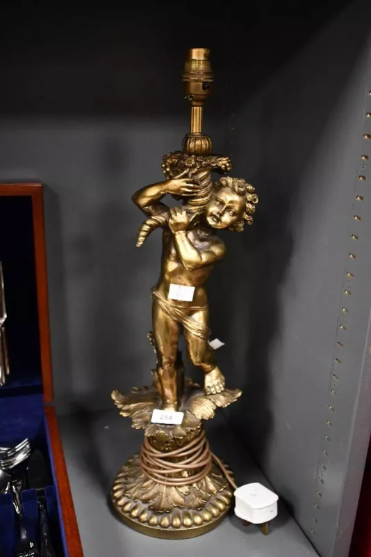A vintage gilt resin figural table lamp, depicting a putto holding a cornocopia upon a rococo-style leaf base, unmarked,