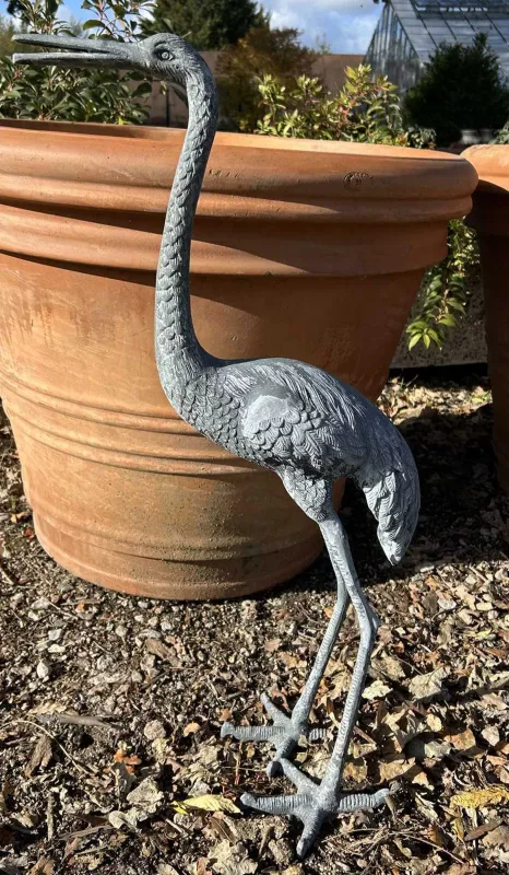A garden sculpture of a Heron or Stork The cast white metal sculpture standing with its neck raised
