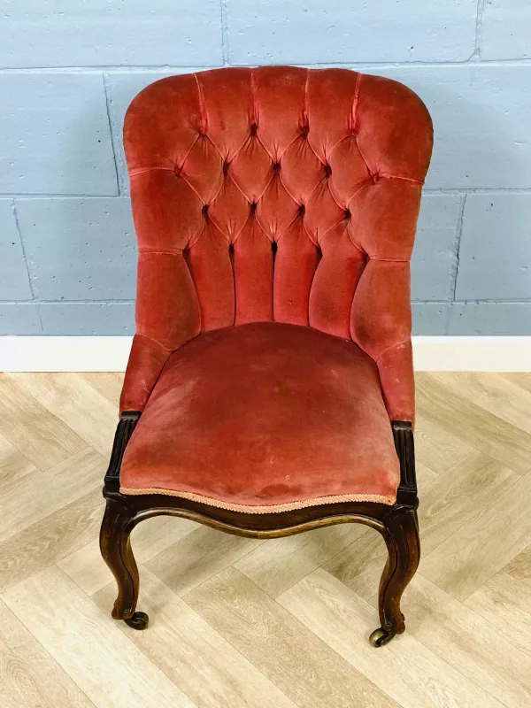 A third quarter 19th century rosewood salon chair with buttoned upholstery and a shaped serpentine seat, raised upon carved cabriole legs with brass castors