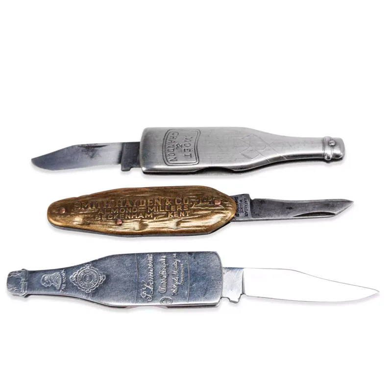 Two Novelty Wine Bottle Pen Knives And An Advertising Knife Early 20th Century two champagne themed by John Watts, Sheffield, the other by Trafalgar Works