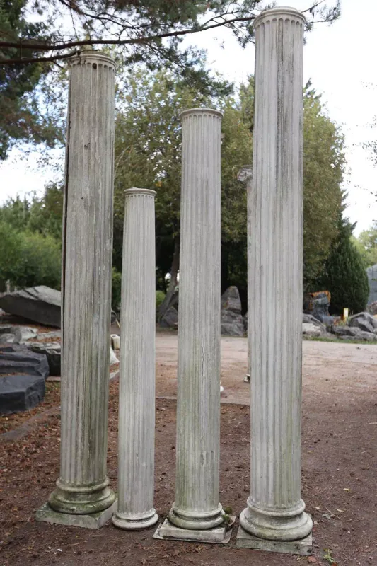 A group of four large fibreglass classical style columns The columns lacking capitals but with fluted shafts and circular socles The tallest